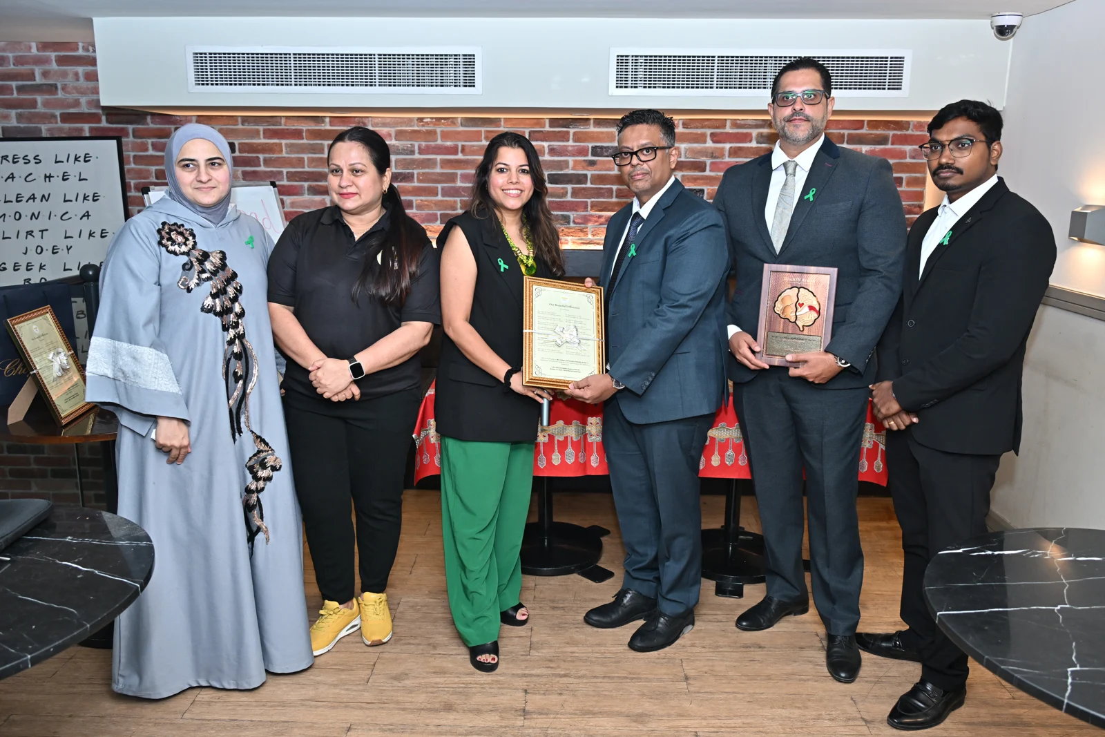 Event participants standing together with framed recognition certificates