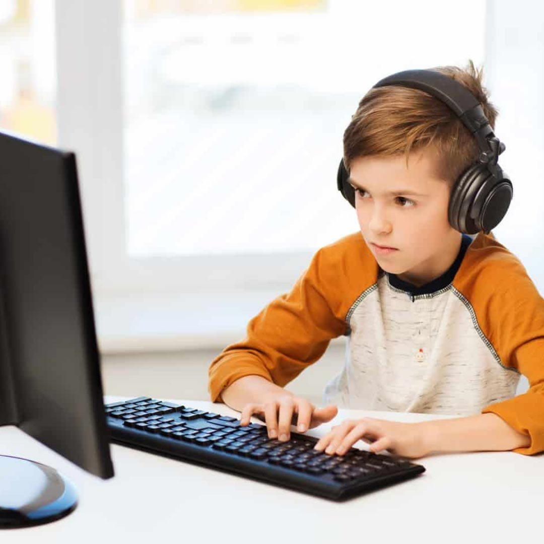A child wearing headphones while using a desktop computer